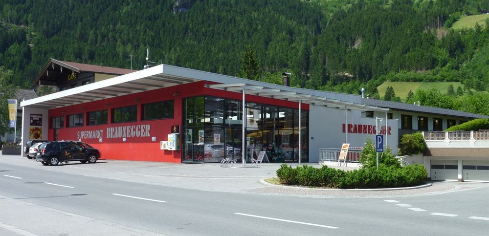 Roter Supermarkt Braunegger in Aschau mit Glasfront vor bewaldetem Berg